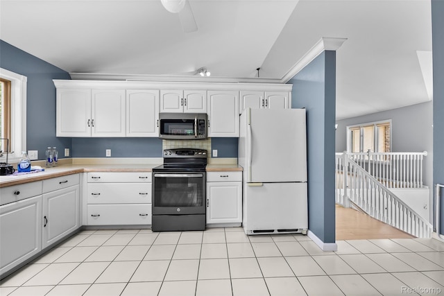 969 Bogie Lake Rd, White Lake, MI 48383 - kitchen with black electric range, freestanding refrigerator, stainless steel microwave, white cabinets, and light countertops