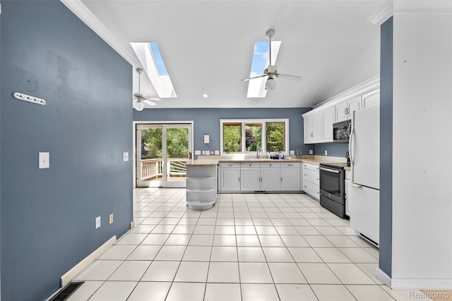 969 Bogie Lake Rd, White Lake, MI 48383 - kitchen with stainless steel appliances, a skylight, ceiling fan, vaulted ceiling, and white cabinetry