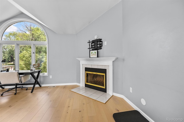 969 Bogie Lake Rd, White Lake, MI 48383 - living room featuring vaulted ceiling, a tiled fireplace, and light wood-style flooring