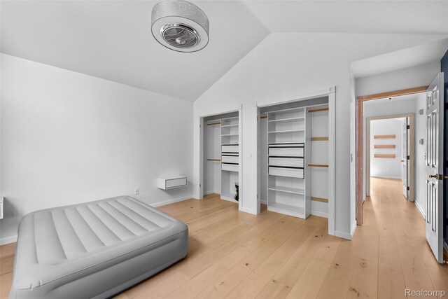 969 Bogie Lake Rd, White Lake, MI 48383 - unfurnished bedroom with lofted ceiling, multiple closets, and light wood-type flooring
