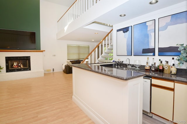 5100 Kings Gate Way, Bloomfield Hills, MI 48302 - kitchen with light wood-style floors, open floor plan, a brick fireplace, dark stone countertops, and a towering ceiling