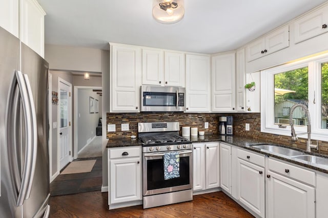 4662 60th St SW, Wyoming, MI 49418 - kitchen with appliances with stainless steel finishes, decorative backsplash, dark stone countertops, and white cabinetry