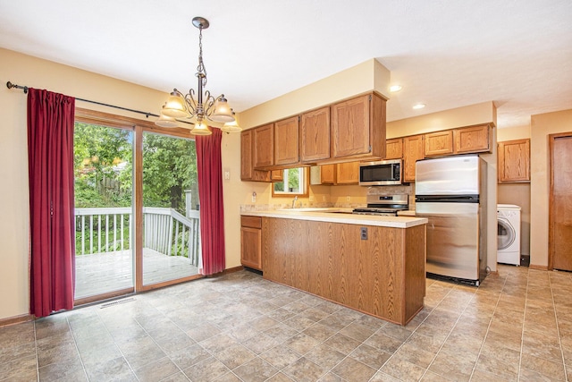 238 Baynton Ave NE, Grand Rapids, MI 49503 - kitchen with appliances with stainless steel finishes, washer / clothes dryer, a peninsula, a chandelier, and light countertops