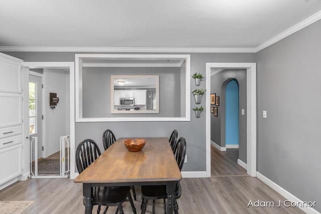 3655 Giddings Ave SE, Grand Rapids, MI 49508 - dining space featuring light wood finished floors, ornamental molding, and arched walkways