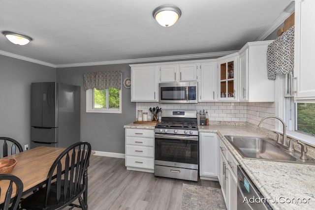 3655 Giddings Ave SE, Grand Rapids, MI 49508 - kitchen with appliances with stainless steel finishes, white cabinets, light countertops, tasteful backsplash, and light wood finished floors