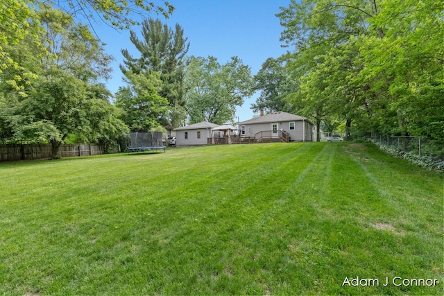 3655 Giddings Ave SE, Grand Rapids, MI 49508 - fenced backyard featuring a trampoline and a wooden deck