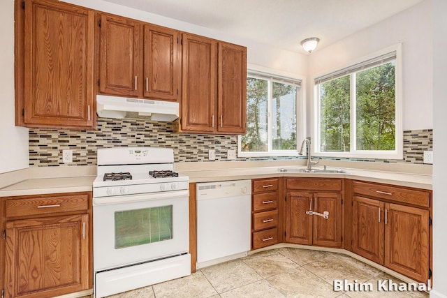 2492 Sunny Creek St SE, Kentwood, MI 49508 - kitchen featuring white appliances, under cabinet range hood, decorative backsplash, brown cabinets, and light countertops