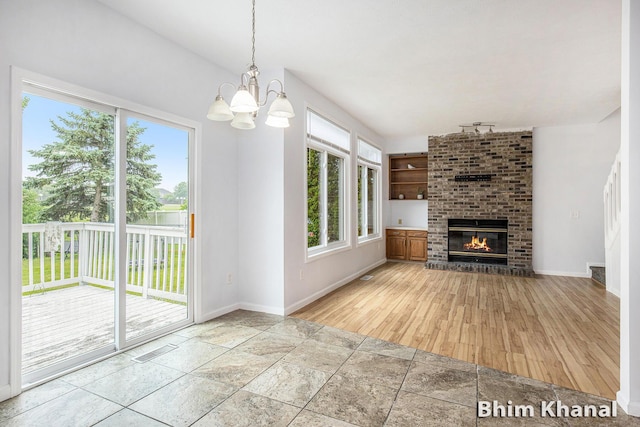 2492 Sunny Creek St SE, Kentwood, MI 49508 - unfurnished living room with plenty of natural light, a chandelier, stone tile flooring, and a brick fireplace