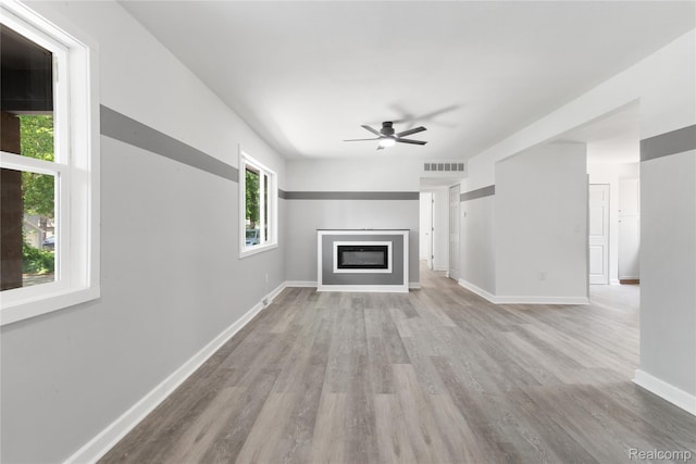 3166 Highland Blvd, Highland, MI 48356 - unfurnished living room featuring a ceiling fan, wood finished floors, and a glass covered fireplace