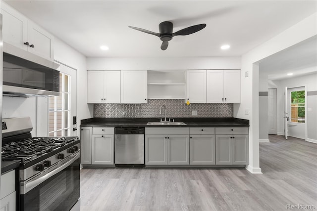 3166 Highland Blvd, Highland, MI 48356 - kitchen featuring appliances with stainless steel finishes, open shelves, dark countertops, light wood finished floors, and backsplash