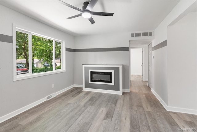 3166 Highland Blvd, Highland, MI 48356 - unfurnished living room featuring wood finished floors, a ceiling fan, and a glass covered fireplace