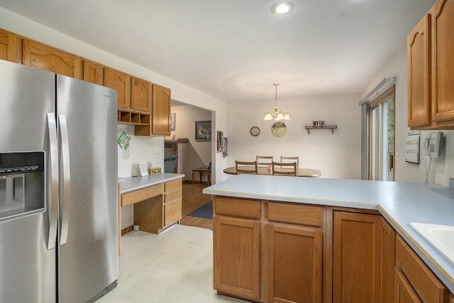 1142 N Peach Ct, Plainwell, MI 49080 - kitchen with stainless steel fridge, a peninsula, light countertops, pendant lighting, and a chandelier