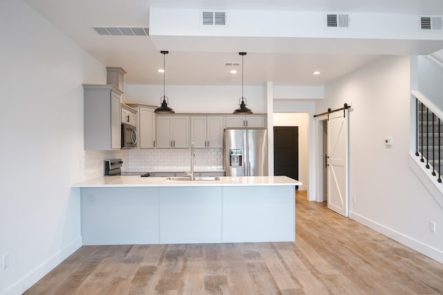 2458 Maes Rd, West Branch, MI 48661 - kitchen with appliances with stainless steel finishes, gray cabinetry, a peninsula, a barn door, and light countertops