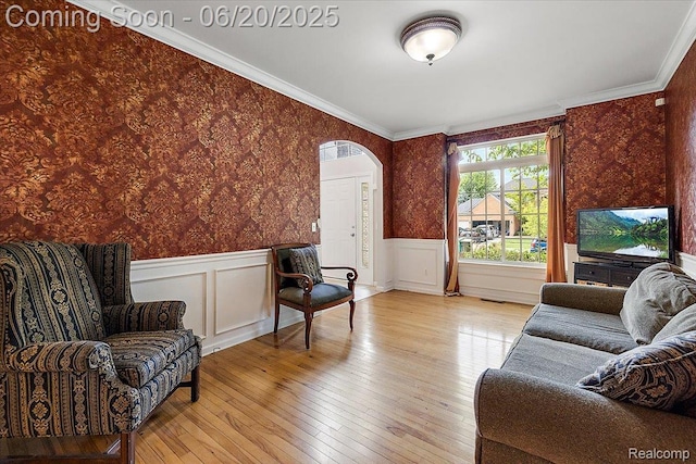 18852 Newbridge Dr, Macomb, MI 48044 - living room featuring wallpapered walls, arched walkways, wainscoting, light wood-style flooring, and ornamental molding