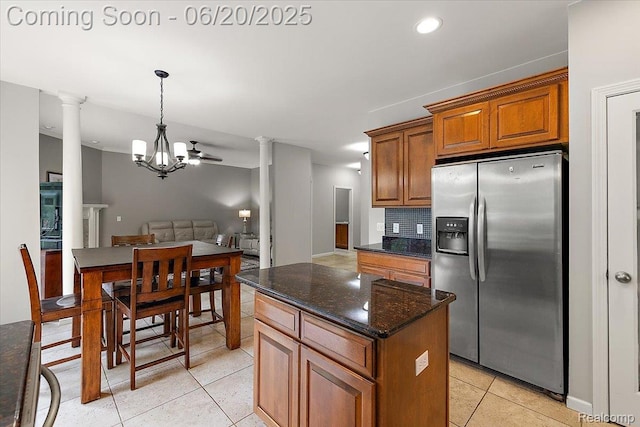 18852 Newbridge Dr, Macomb, MI 48044 - kitchen featuring stainless steel fridge with ice dispenser, ornate columns, brown cabinets, light tile patterned flooring, and a center island