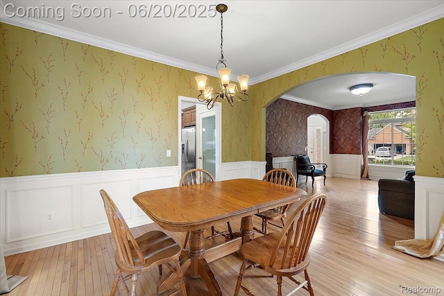 18852 Newbridge Dr, Macomb, MI 48044 - dining area featuring arched walkways, light wood-type flooring, a wainscoted wall, wallpapered walls, and a chandelier