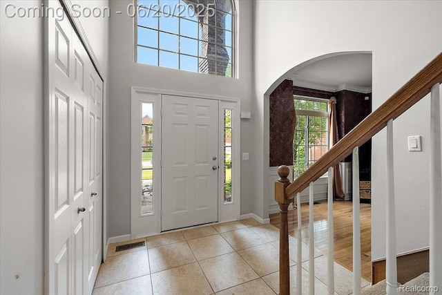 18852 Newbridge Dr, Macomb, MI 48044 - entrance foyer featuring arched walkways, light tile patterned flooring, a towering ceiling, and stairway