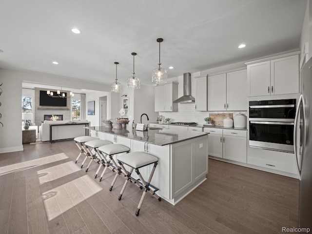 24654 Floret, Macomb, MI 48042 - kitchen with wall chimney exhaust hood, recessed lighting, a kitchen breakfast bar, dark wood-style flooring, and dark stone counters