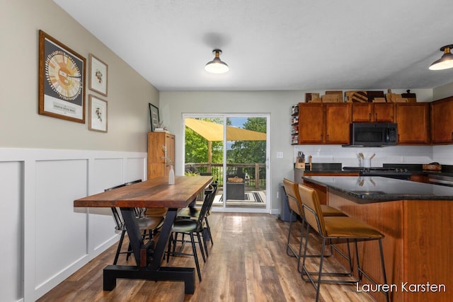 14734 Crescent Meadows Dr, Cedar Springs, MI 49319 - kitchen with black microwave, a breakfast bar area, dark wood-style floors, brown cabinets, and wainscoting