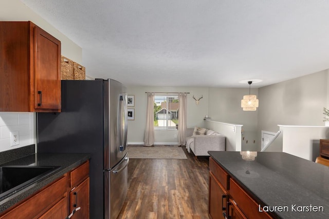 14734 Crescent Meadows Dr, Cedar Springs, MI 49319 - kitchen with dark wood-style flooring, dark countertops, freestanding refrigerator, open floor plan, and decorative light fixtures