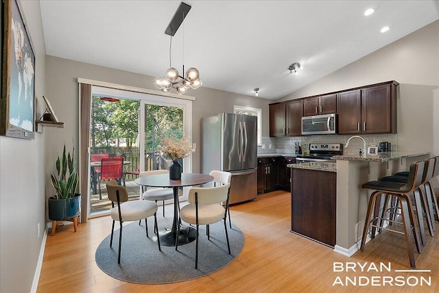 1910 Hall St SE, Grand Rapids, MI 49506 - kitchen with appliances with stainless steel finishes, dark brown cabinets, light wood-style floors, decorative backsplash, and light stone countertops