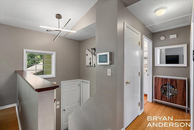1910 Hall St SE, Grand Rapids, MI 49506 - corridor featuring wood finished floors, a textured ceiling, an upstairs landing, and a chandelier