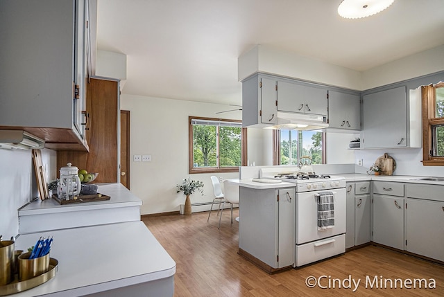 7080 Pine Island Dr NE, Comstock Park, MI 49321 - kitchen with gas range gas stove, gray cabinets, a peninsula, and under cabinet range hood