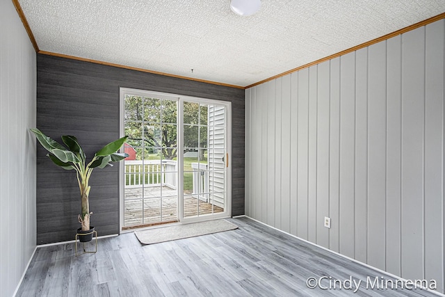 7080 Pine Island Dr NE, Comstock Park, MI 49321 - doorway with ornamental molding, wood finished floors, wooden walls, and a textured ceiling