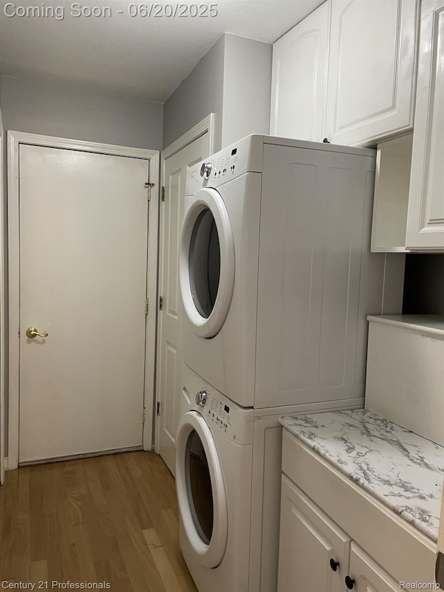 6850 Deerhurst Dr, Westland, MI 48185 - washroom featuring stacked washing machine and dryer, light wood finished floors, and cabinet space