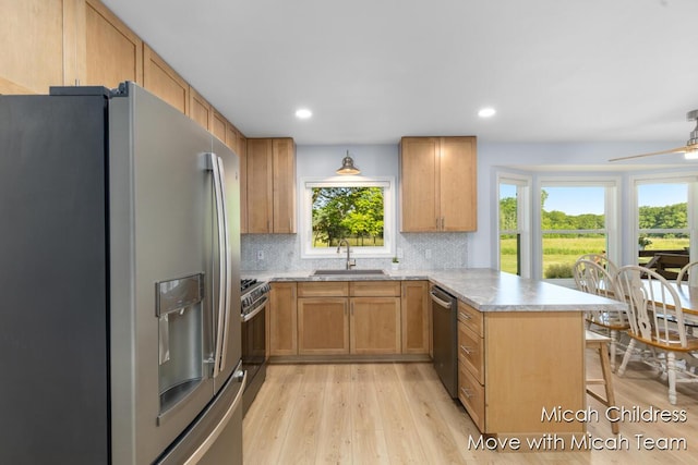 10829 26th Ave NW, Grand Rapids, MI 49534 - kitchen featuring stainless steel appliances, a peninsula, light wood-style floors, tasteful backsplash, and a kitchen breakfast bar