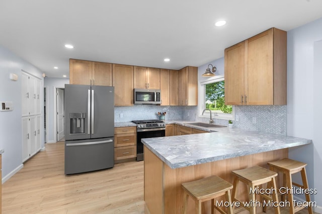 10829 26th Ave NW, Grand Rapids, MI 49534 - kitchen with appliances with stainless steel finishes, light countertops, light wood finished floors, a peninsula, and recessed lighting