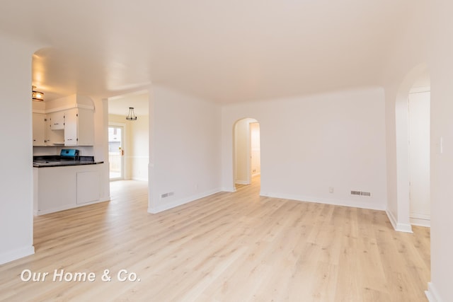 1716 Sycamore St, Saginaw, MI 48602 - unfurnished living room featuring light wood-style floors and arched walkways