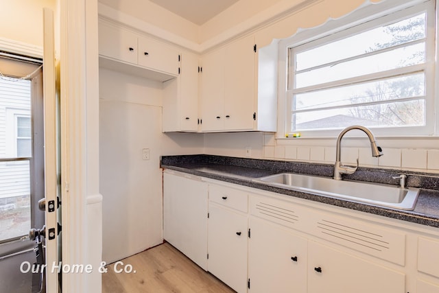 1716 Sycamore St, Saginaw, MI 48602 - kitchen featuring dark countertops, white cabinets, and light wood-type flooring
