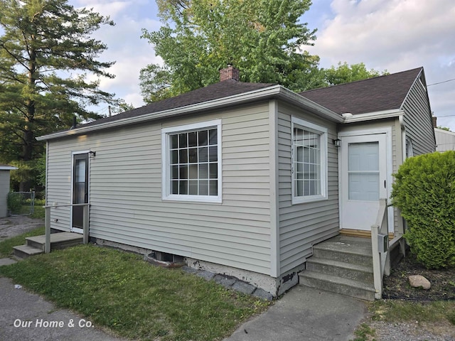1716 Sycamore St, Saginaw, MI 48602 - view of side of property featuring entry steps, a chimney, and a shingled roof