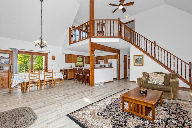 8651 22 Mile Rd NE, Sand Lake, MI 49343 - living room with high vaulted ceiling, stairway, a chandelier, ceiling fan, and wood finished floors