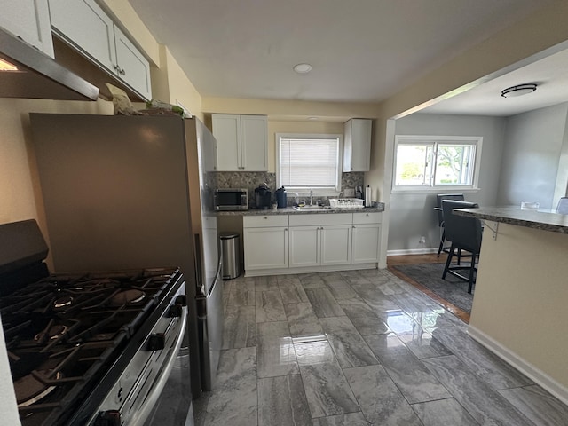 29635 Julius Blvd, Westland, MI 48186 - kitchen with stainless steel appliances, under cabinet range hood, white cabinetry, tasteful backsplash, and stone countertops