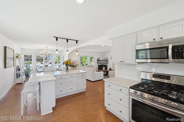 13368 N Fenton Rd, Fenton, MI 48430 - kitchen featuring appliances with stainless steel finishes, arched walkways, a center island, tasteful backsplash, and white cabinetry