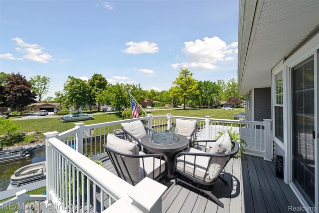 13368 N Fenton Rd, Fenton, MI 48430 - wooden deck featuring outdoor dining space, a lawn, a water view, and view of scattered trees