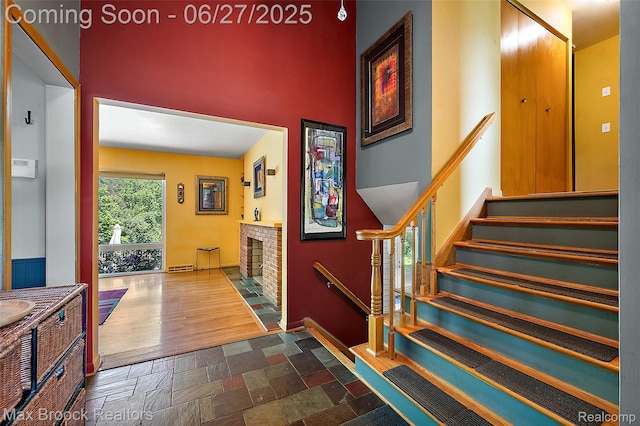 7189 Lindenmere Dr, Bloomfield Hills, MI 48301 - stairway featuring stone finish flooring, a brick fireplace, and a towering ceiling