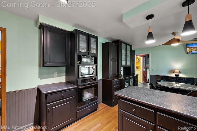 7189 Lindenmere Dr, Bloomfield Hills, MI 48301 - kitchen with black appliances, dark countertops, wainscoting, light wood-style floors, and glass insert cabinets