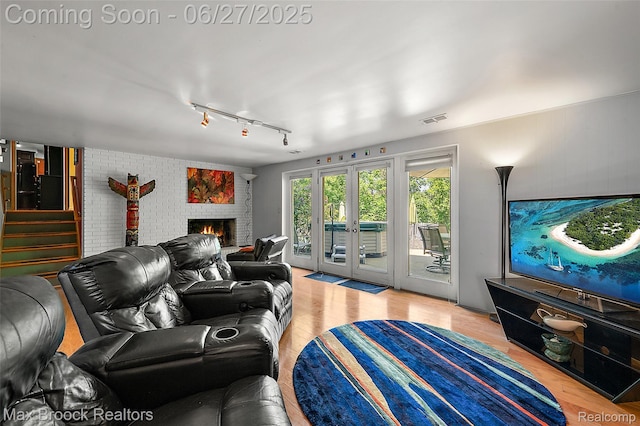 7189 Lindenmere Dr, Bloomfield Hills, MI 48301 - living area featuring wood finished floors, rail lighting, stairs, a fireplace, and brick wall