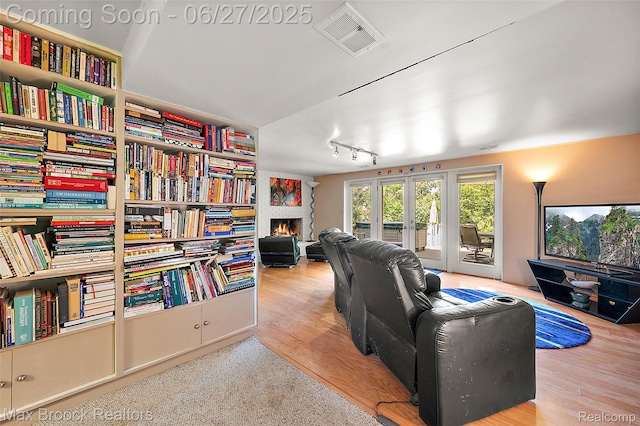 7189 Lindenmere Dr, Bloomfield Hills, MI 48301 - living room featuring a warm lit fireplace, french doors, track lighting, and wood finished floors