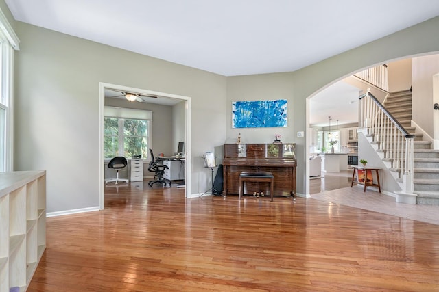 7639 Dunross Dr, Portage, MI 49024 - living area featuring light wood-style flooring, arched walkways, stairway, ceiling fan, and a desk