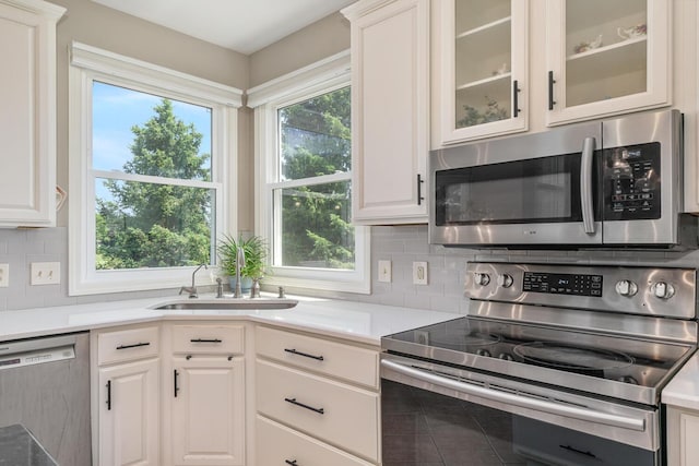 7639 Dunross Dr, Portage, MI 49024 - kitchen with stainless steel appliances, tasteful backsplash, glass insert cabinets, light countertops, and white cabinetry