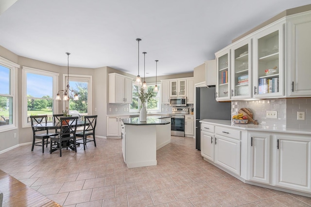 7639 Dunross Dr, Portage, MI 49024 - kitchen featuring stainless steel appliances, decorative backsplash, a center island, white cabinetry, and glass insert cabinets
