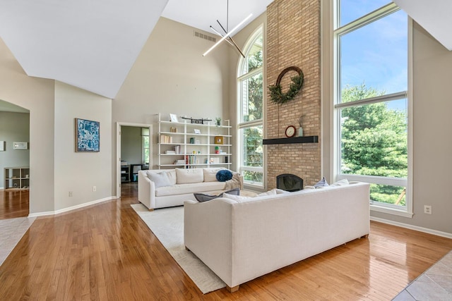 7639 Dunross Dr, Portage, MI 49024 - living area featuring a towering ceiling, light wood-style flooring, a fireplace, and plenty of natural light