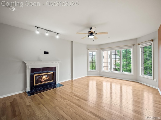 1539 Bartley Ln, Bloomfield Hills, MI 48304 - unfurnished living room featuring ceiling fan, a tiled fireplace, wood finished floors, and track lighting