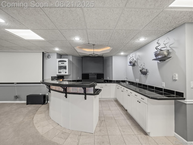 1539 Bartley Ln, Bloomfield Hills, MI 48304 - kitchen with dark countertops, recessed lighting, white cabinets, a breakfast bar area, and a peninsula