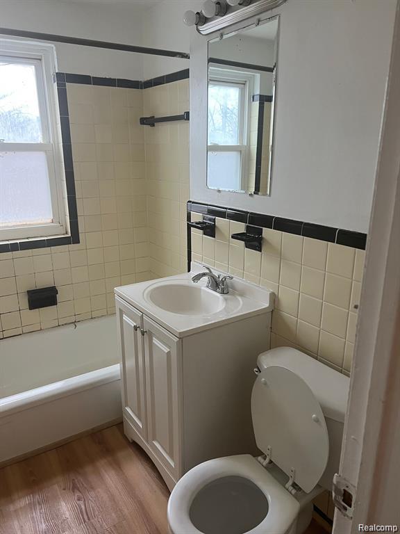 17710 Chester St, Detroit, MI 48224 - full bathroom with vanity, bathing tub / shower combination, tile walls, and wood finished floors