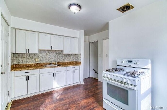 17710 Chester St, Detroit, MI 48224 - kitchen with white gas range, dark wood-style flooring, backsplash, white cabinetry, and dark stone countertops